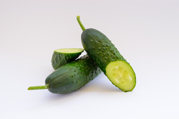 sliced cucumbers are laying on the white plain background. Fresh vegetables, vegetarian food, green. 