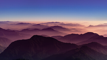 Naklejka na ściany i meble View of Himalayas mountain range with visible silhouettes through the colorful fog from Khalia top trek trail. Khalia top is at an altitude of 3500m himalayan region of Kumaon, Uttarakhand, India.