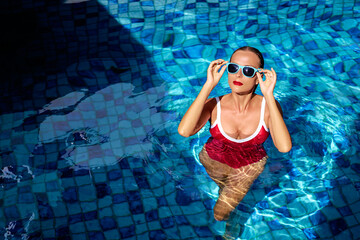 Summer vacation and fashion. Beautiful young woman in red swimsuit at swimming pool.