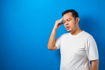 Portrait of good looking young Asian man in white t-shirt having stress or pain of headache,...