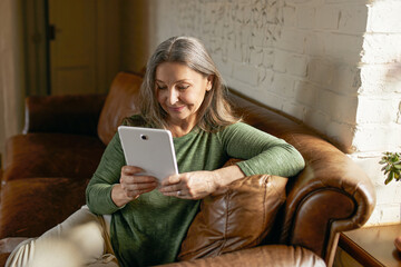 People, aging and electronic gadgets. Modern attractive middle aged woman with long gray hair...