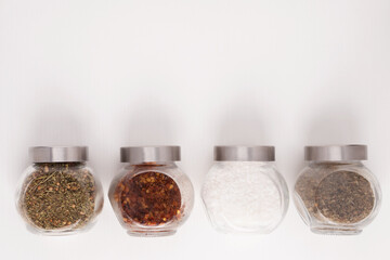Set for cooking delicious dishes. Mix of spices in jars. Different herbs, sea salt, hot pepper