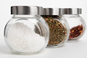 Set for cooking delicious dishes. Mix of Italian and Greek herbs, coarse sea salt, hot chili pepper on a white plate with copyspace