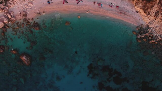 Aerial drone view of Eremitis beach on Paxos Iceland, Greece, at sunset, in summer, with people on the beach