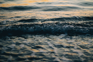 Sea white foam on the crest of a wave. Bubbling water. The wave runs ashore. Sea waves at dawn.