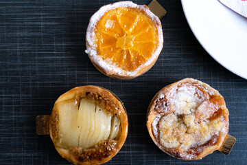 close up of three sorts of french tarts with fruits and powdered sugar in top view