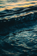 Sea white foam on the crest of a wave. Bubbling water. The wave runs ashore. Sea waves at dawn.