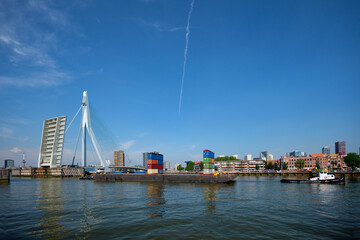 Fototapeta na wymiar Tug boat towing barge with containers under open bascule part of Erasmusbrug bridge in Nieuwe Maas river. Rotterdam, Netherlands