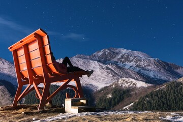 Women siting on big bench in mountains Prato nevoso resort at night in Piedmont Alps Italy