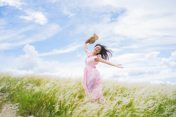 Fototapeta na wymiar Asian woman is refreshing at the meadow. She jumps.