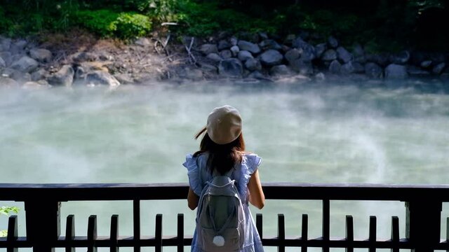 Young woman traveler looking at Hot spring pond at Xinbeitou thermal valley in Taiwan