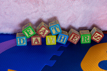 A fathers day message written out with children's wooden toy letter blocks on a play mat