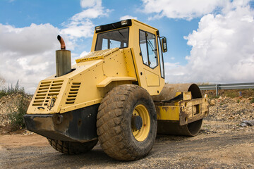 Yellow steamroller doing road construction work