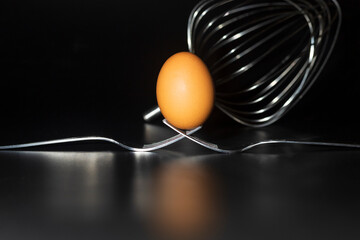 Organic fresh egg standing on two joined fork on black background