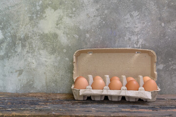 raw chicken eggs in egg box on the old wooden table with cement walls background. - 355904375
