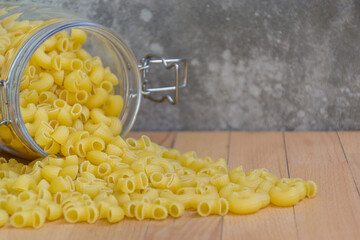 Close-up of Macaroni in a glass jar placed on the wooden table , selective focus. - 355904950