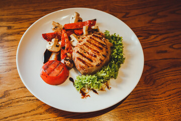 Grilled piece of chicken breast with vegetables on a white plate