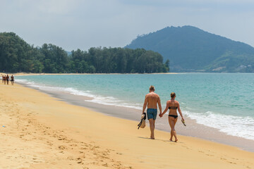 Couple holding hands walking at white sand tropical beach with blue sky in Phuket,Thailand - 355905101