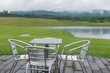 table and chairs outside in garden with a pond or lake and landscape background in Thailand. - 355905517
