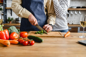 Cropped image of beautiful senior couple in apron cooking together at kitchen