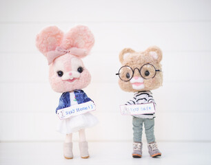 Stay Home Stay Safe concept. cute felt dolls holding label saying stay home and stay safe during the spread of Covid Virus.