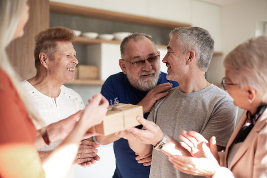 friends congratulating an elderly couple on their housewarming.