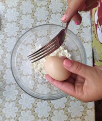 woman confectioner breaks egg in bowl for muffins
