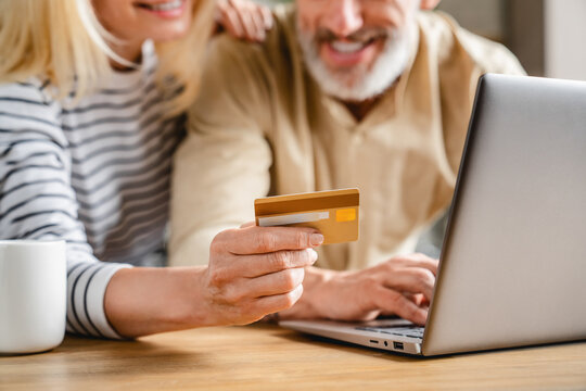 Cropped image of middle aged couple making online shopping with credit card at home