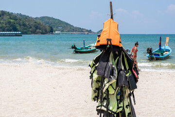 Life jackets hang for tourists to use on the beach in Phuket,Thailand. - 355906920