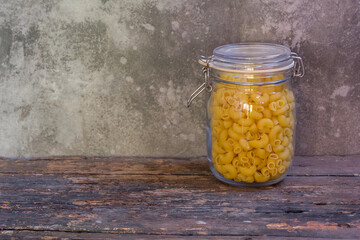 Macaroni in a glass jar placed on the old wood table on the table, selective focus - 355907574
