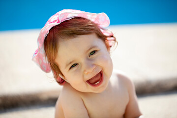 Niña de quince meses con gorrito junto a la piscina