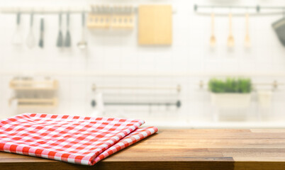 Red fabric,cloth on wood table top on blur kitchen counter (room)background