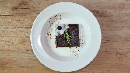 Homemade chocolate brownies in white plate on wooden table, Top view