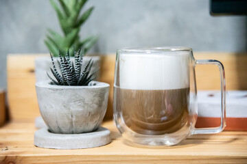 hot coffee in double layer glass with cactus in cement pot.
