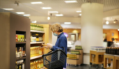 Supermarket shopping, face mask and gloves,Young man shopping in supermarket, reading product information