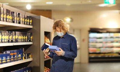 Supermarket shopping, face mask and gloves,Young man shopping in supermarket, reading product information