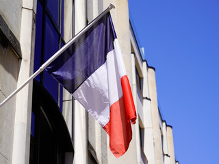 French flag waving in front facade of city hall in town of france