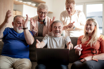 group of old friends watch a video on their laptop.