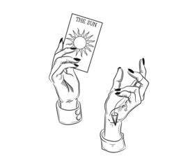 Hands holding a tarot card. The witch bodes from tarot cards, sun, spells and magic
