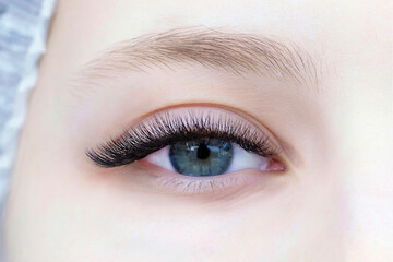 Eyelash extensions. Close-up of eye with extended eyelashes of a white girl