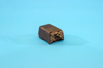 bitten chocolate candy isolated on a blue background.A piece of candy
