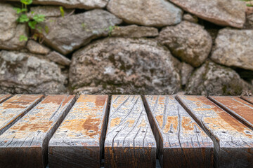 a flat board of old rough wood texture placed in front of an old stone background.