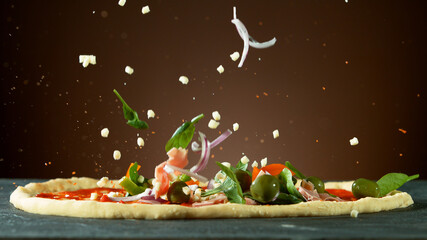 Fototapeta na wymiar Falling raw ingredients on pizza