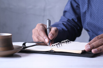 young man writing on notepad at office desk 