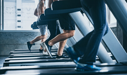 Fototapeta na wymiar Sporty people running on treadmills machine in gym, Fitness exercise concept, group of young strong people training in modern gym, Shot focus on legs
