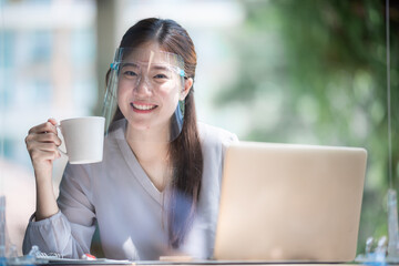 Asian women wearing face shield at the coffee cafe, a way to prevent communicable diseases but...