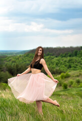 Fototapeta na wymiar Beautiful girl in pink skirt posing on natural landscape. Young woman relaxing