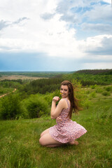 Fototapeta na wymiar Happy young girl in short dress sitting and having fun. Beautiful spring landscape. 