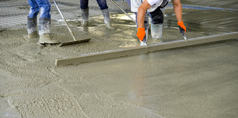 workers leveling concrete of a new building