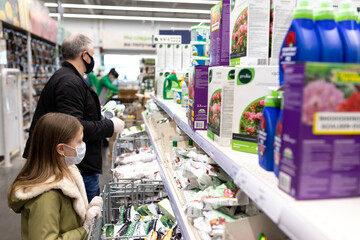 Father and daughter in a construction store in medical protective masks and disposable gloves